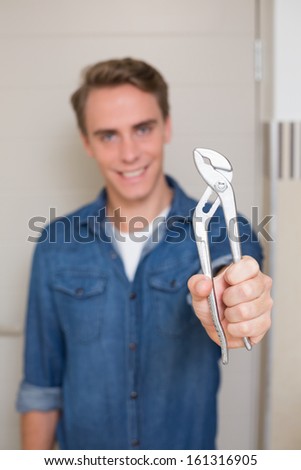 Portrait of a smiling young handyman holding out wrench