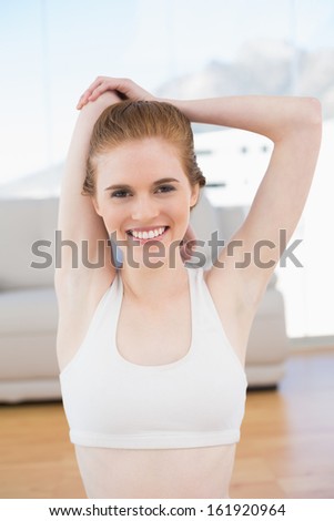 Portrait of a sporty young woman stretching hands behind back in fitness studio