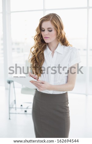 Young elegant businesswoman writing notes in a bright office