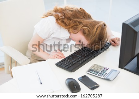 High angle view of a young businesswoman resting head on keyboard in the office