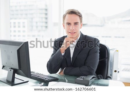 Portrait of a smiling young businessman in front of computer at office desk
