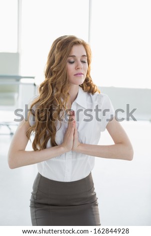 Worried elegant businesswoman kneeling with joined hands in a bright office