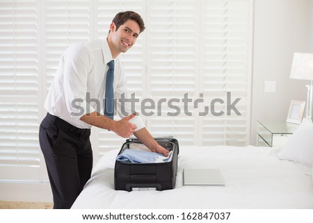 Side view portrait of a smiling businessman unpacking luggage at a hotel bedroom