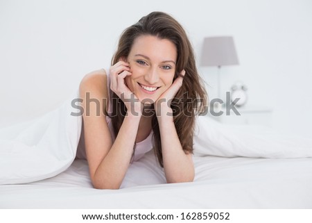 Portrait of a pretty smiling young woman resting in bed at home
