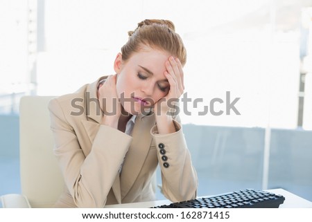 Young businesswoman with neck pain in front of computer at office desk
