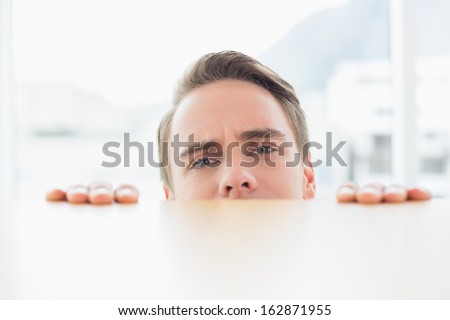 Close up portrait of a young businessman looking over blurred wall at bright office