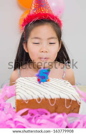 Close-up of a cute little girl blowing her birthday cake