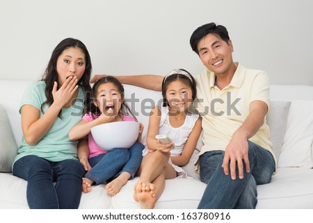 Portrait of a happy family of four watching tv in the living room at home