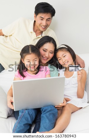 Happy family of four doing online shopping through laptop and credit card at home