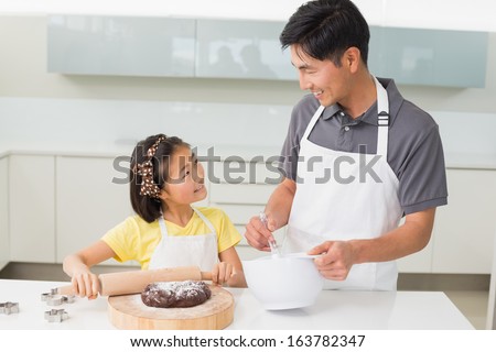 Smiling young man with his daughter preparing cookies in the kitchen at home