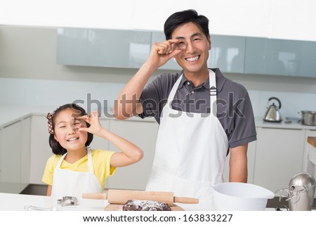 Portrait of a happy young girl with her father holding cookie molds in the kitchen at home