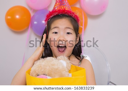 Close-up portrait of a shocked little girl with gift at her birthday party