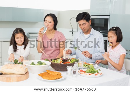 Young family of four enjoying healthy meal in the kitchen at home