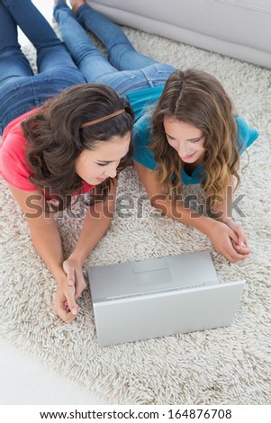 High angle view of two young female friends using laptop in the living room at home