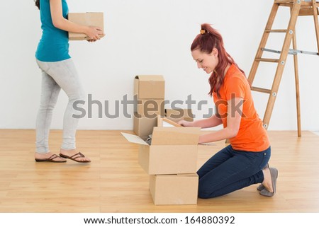 Two friends moving together in a new house and unwrapping boxes