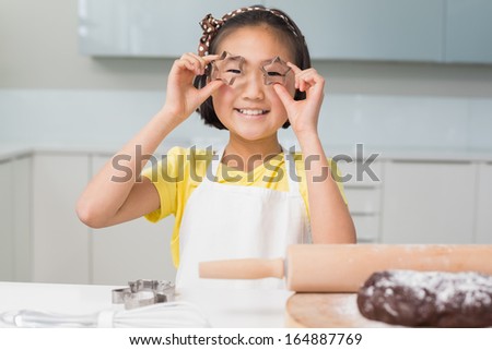 Portrait of a smiling young girl holding cookie molds in the kitchen at home