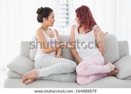 Relaxed young female friends chatting in the living room at home