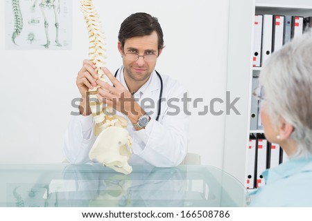 Portrait of a male doctor explaining the spine to a senior patient in medical office