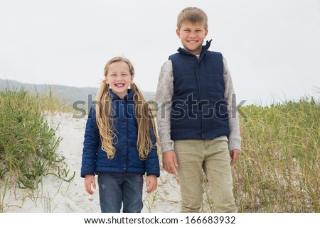 Portrait of a happy brother and sister standing at the beach