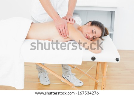 Male physiotherapist massaging woman\'s back in the medical office