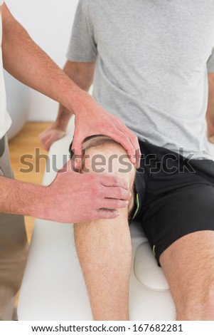 Close-up mid section of a young man getting his knee examined at the medical office