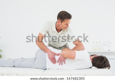 Male physiotherapist examining man\'s back in the medical office