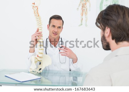 Male doctor explaining the spine to a patient in medical office