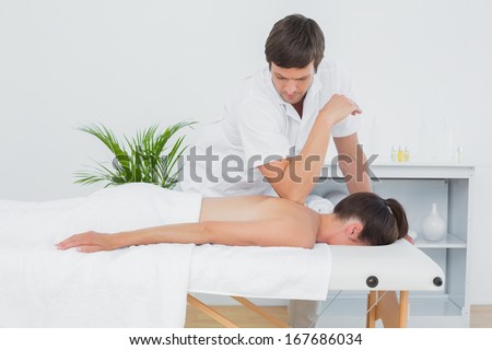 Male physiotherapist massaging woman\'s back in the medical office