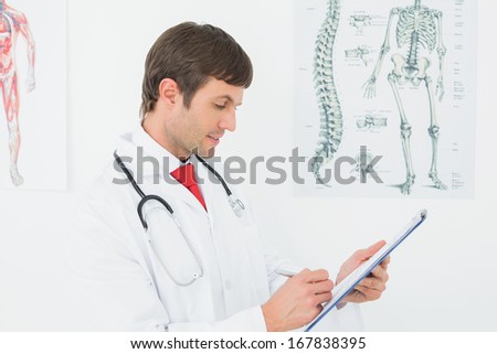 Concentrated male doctor writing reports in the medical office
