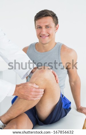Portrait of a smiling young man getting his leg examined at the medical office