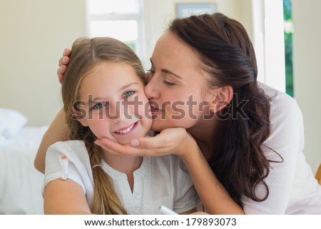 Loving mother kissing daughter at home