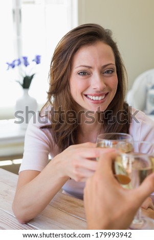 Close-up of a smiling young woman toasting wine glass at home