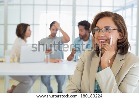 Close-up of a smiling businesswoman with colleagues in meeting in background at the office