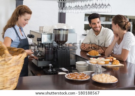 Side view of a smiling couple with female cafe owner at the coffee shop