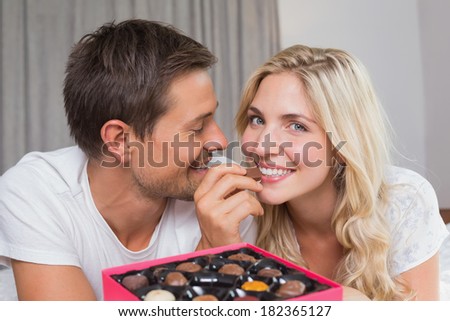 Relaxed happy young couple eating candies at home