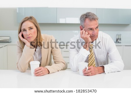 Unhappy business couple not talking after an argument in the kitchen at home