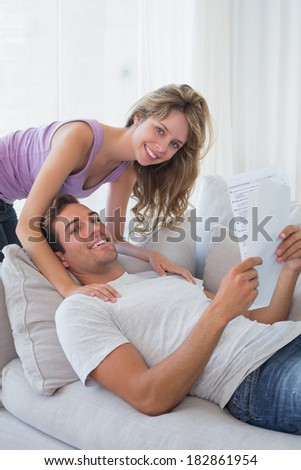 Portrait of a loving relaxed young couple reading document on couch at home