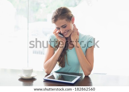 Young woman with coffee cup using digital tablet and cellphone at counter in the coffee shop