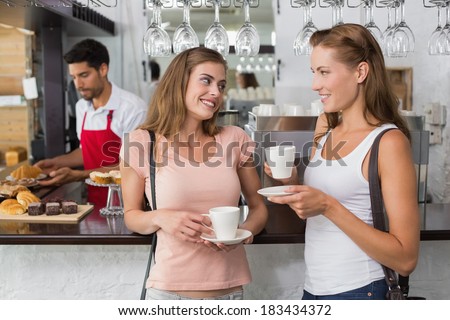 Portrait of female friends with male barista at counter in the coffee shop