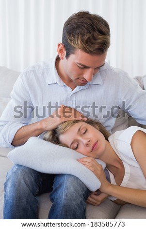 Relaxed young woman resting on mans lap on couch at home