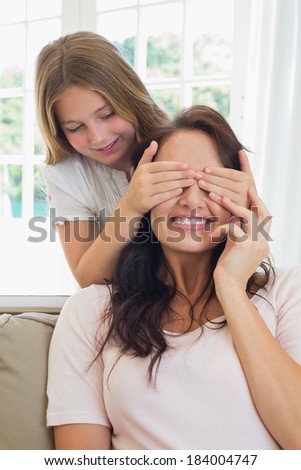 Cute girl covering eyes of mother in house