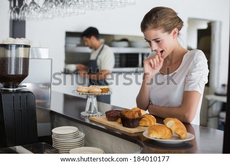 Side view of a thoughtful young woman looking at sweet food at the coffee shop