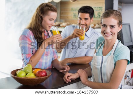 Portrait of a smiling waitress with couple drinking orange juice at the coffee shop