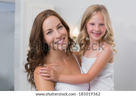 Portrait of a smiling mother carrying daughter in the house