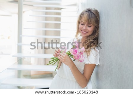 Side view of a beautiful young woman with flowers standing on stairs at home