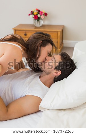 Side view of a relaxed young couple kissing in bed at home