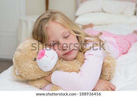 Close-up of a young girl sleeping with stuffed toy in bed at home