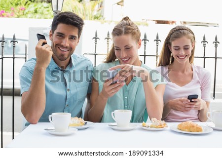 Portrait of three happy friends reading text message in the cafÃ?Â©