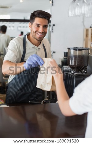 Friendly male waiter giving packed food to a woman at the coffee shop