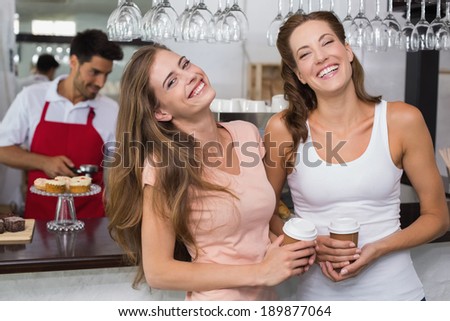 Cheerful female friends with male barista at counter in the coffee shop
